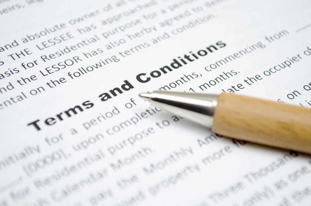 A close-up of a document with the heading "Terms and Conditions" in bold, alongside a wooden pen.