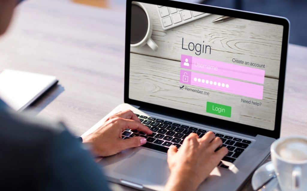 A person typing on a laptop showing a login screen with username and password input fields.