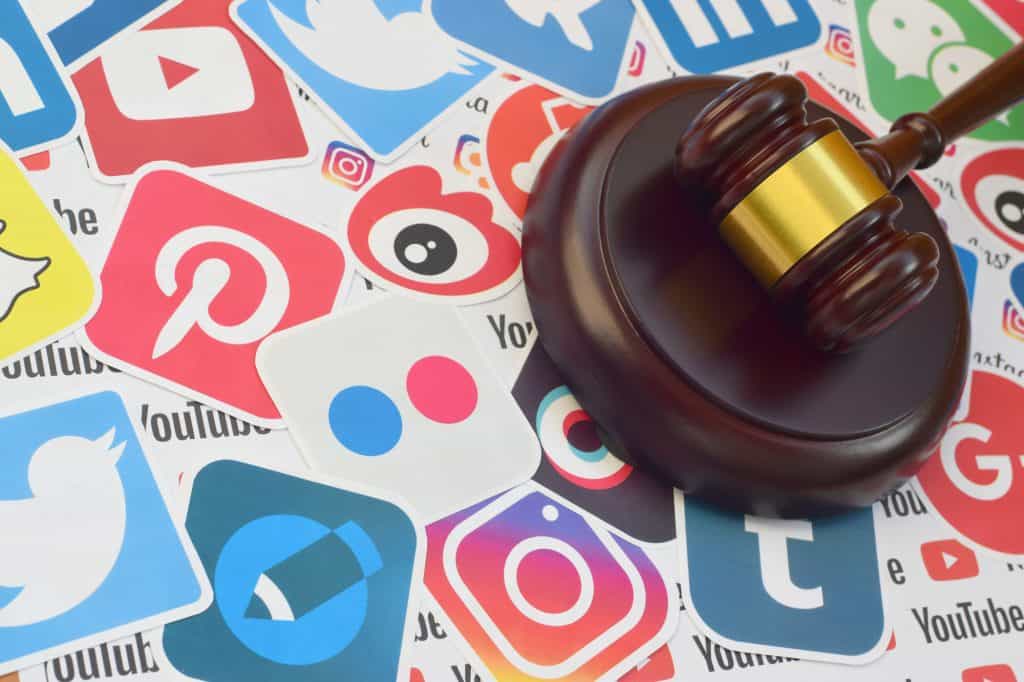 A wooden gavel resting on top of scattered social media logos, including platforms like Pinterest, Instagram, and Twitter.