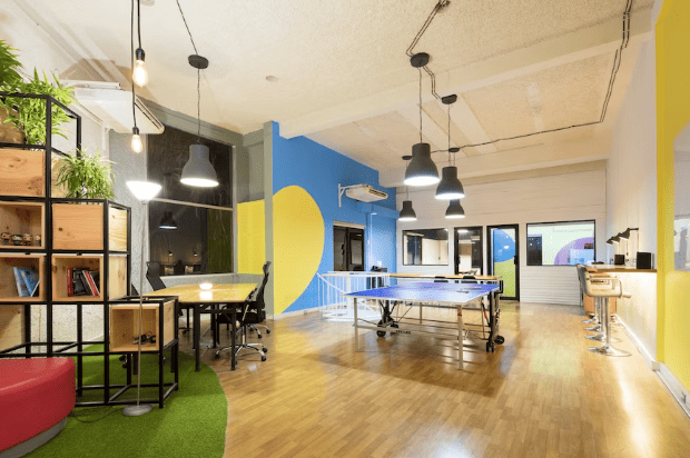 An office interior enhanced by vibrant paintings showcasing shades of yellow and blue, with a ping pong table occupying a central spot.